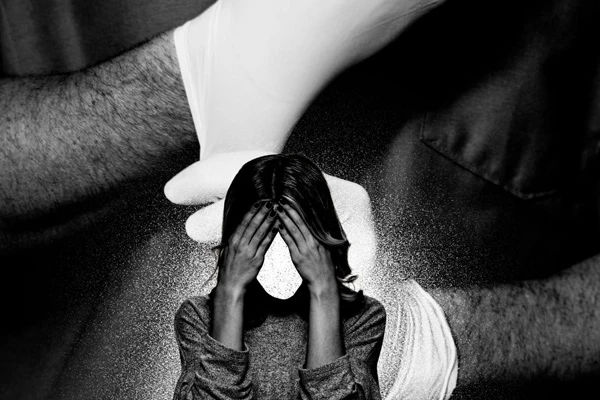 A faceless woman holding her head in her hands. In the background, a male doctor is putting on white medical gloves. Photo Illustration by Luis G. Rendon/The Daily Beast/Getty